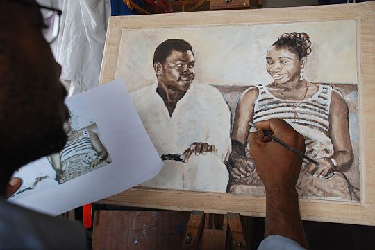 アーティスト、パパケイの描くポピシとモミシ（ナイジェリア英語で、「父さんと母さん」の意）の肖像画。ラゴスの写真館で1976年に撮った、結婚してまもないころのふたりの写真を貸りて、それをもとに、パパケイに油彩で描いてもらった。ナイジェリアでは、アーティストに依頼して、肖像写真を肖像画にしてもらい、居間に飾ることがしばしば好まれる。贈りものとしても、価値の高いものとして喜ばれる。2010年7月22日、イフェ、モーレ地区のパパケイのアトリエにて。